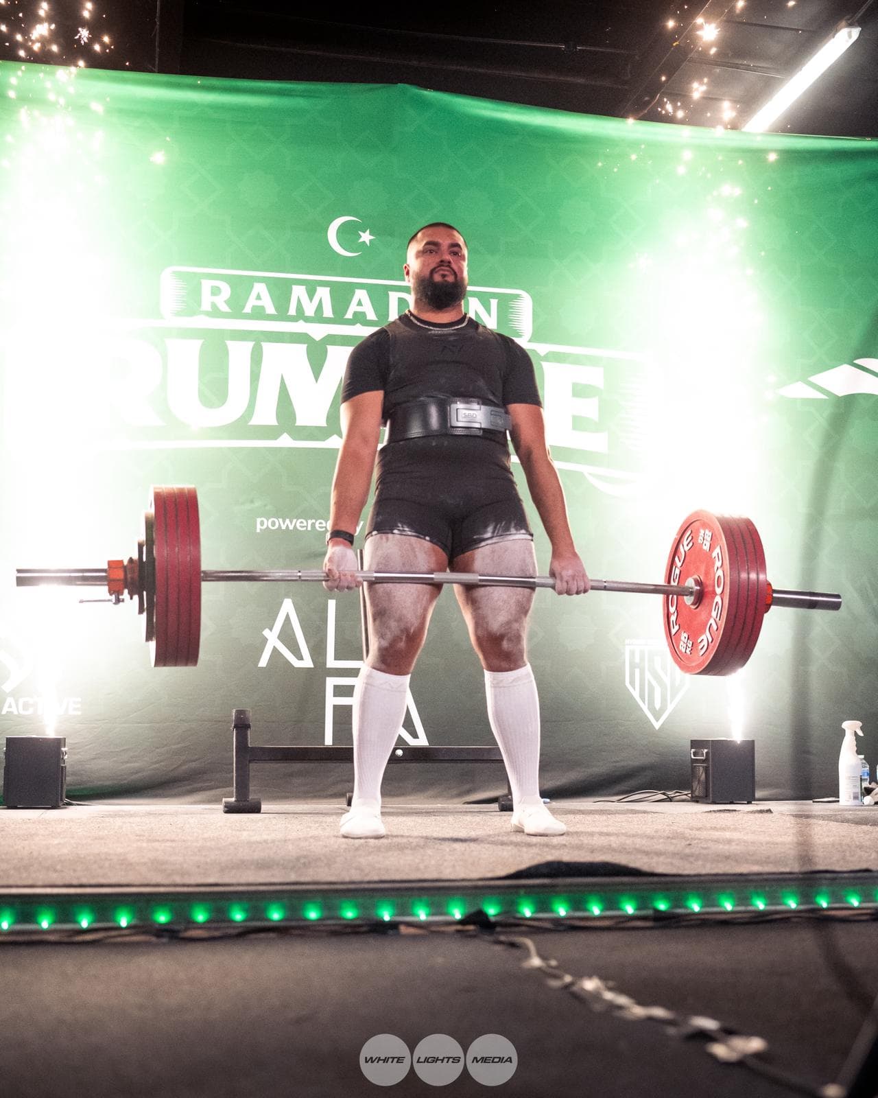 A lifter completing a heavy deadlift on stage at the RR Strength Ramadan Rumble charity event